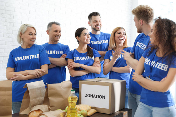 Team of volunteers near table with food donations indoors - Фото, зображення