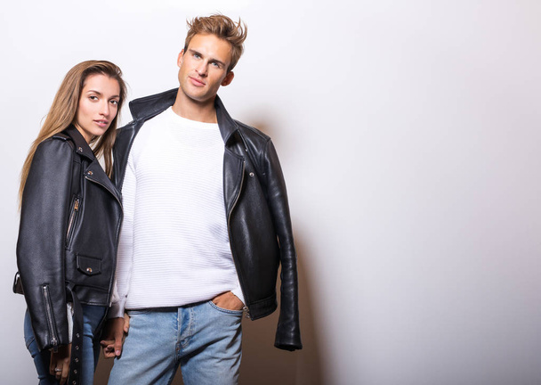 Young beautiful couple in black leather jackets pose in studio. - Foto, imagen