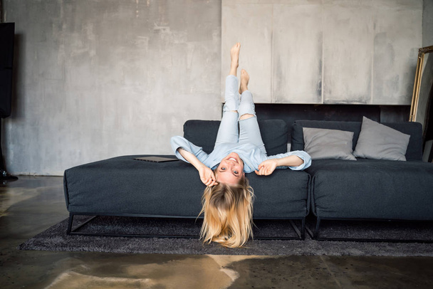 Woman enjoying on a couch with head upside down. - Fotoğraf, Görsel