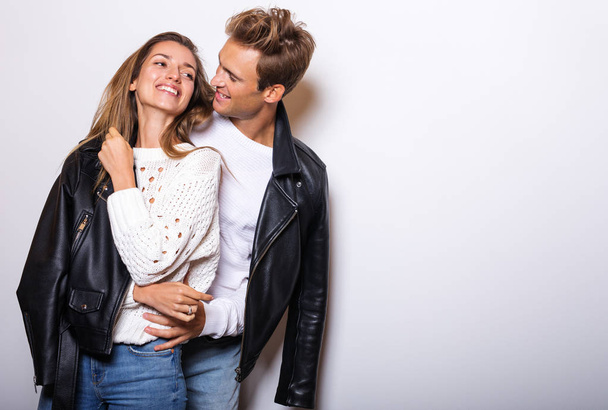Young beautiful couple in black leather jackets pose in studio. - Photo, image