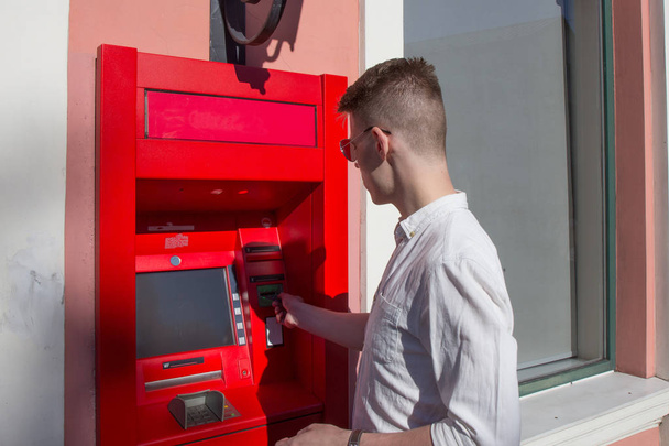 Jeune homme utilisant un distributeur automatique
 - Photo, image