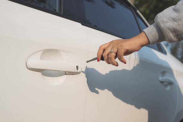 A hand opening a car door with a key - 写真・画像