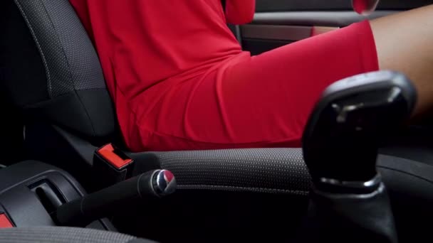 Kobieta w czerwonej sukni mocowania pasa bezpieczeństwa samochodowego siedząc wewnątrz pojazdu przed jazdą - Materiał filmowy, wideo