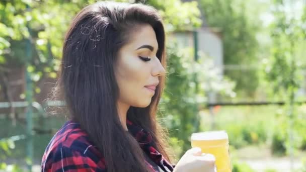 Portret młodej szczęśliwej kobiety pije piwo ze szkła, gaje pragnienie, w ogrodzie przy grillu - Materiał filmowy, wideo