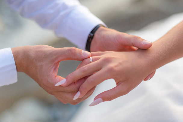Groom slipping ring on finger of bride at wedding - Фото, зображення