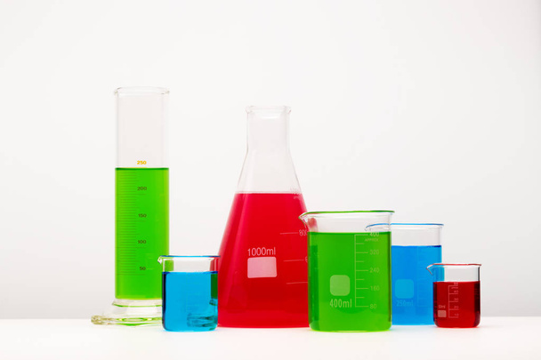 Laborgläser mit Flüssigkeiten in verschiedenen Farben auf dem Tisch. - Foto, Bild