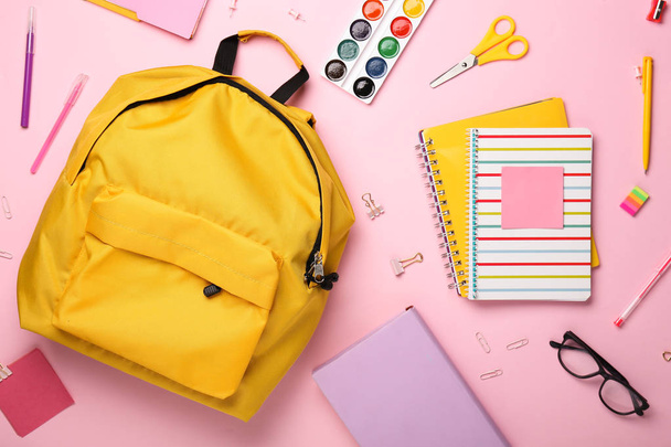 School backpack and stationery on color background - Fotó, kép