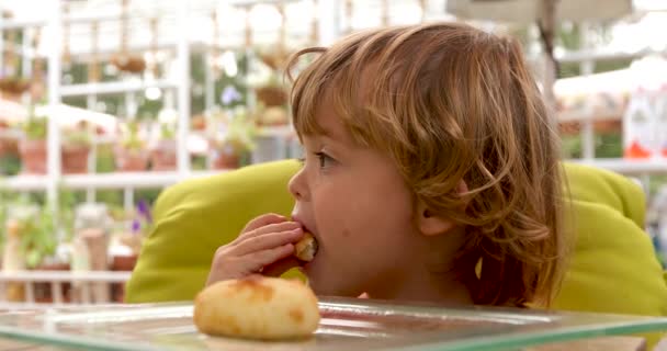 Niño reflexivo comiendo pan en la mesa en la cafetería
 - Imágenes, Vídeo