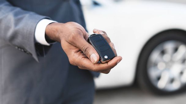 Afro man holding keys with white auto on background - Photo, Image