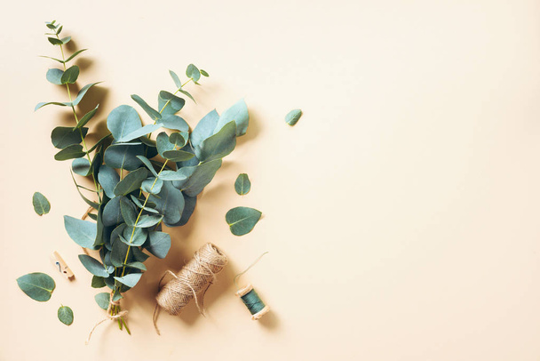 Eucalyptus bouquet creating with baby blue eucalyptus branches over pastel background. Florist work concept. Top view. Flat lay. - Фото, изображение
