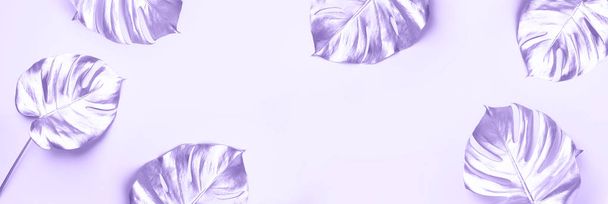 Exotic summer trend in minimal style. Golden tropical palm monstera leaf on trendy violet color background. Shiny and sparkle design, fashion concept. - Zdjęcie, obraz