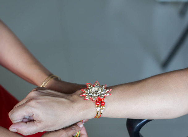 рука жінки, що зв'язує рахі в руці хлопця під час індуїстського ритуалу ракшабанда з вибірковим фокусом
 - Фото, зображення