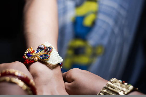 hand of a lady tying rakhi in hand of a guy during the hindu ritual of rakshabandhan with selective focus - Fotoğraf, Görsel