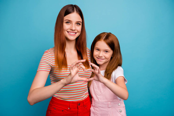 Pretty foxy little lady and her mom making heart figure with help of hands wear casual clothes isolated blue background - Фото, зображення