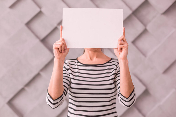 Woman covering her face with a blank poster - Photo, Image