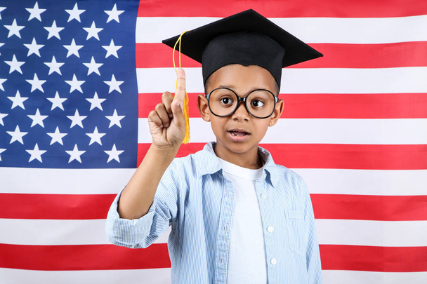 Cute boy in graduation cap on american flag background - Foto, Imagem