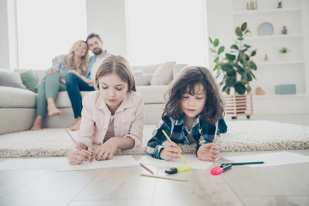Photo of big family two children comfortable lying floor fluffy carpet making drawings while parents sit sofa - Φωτογραφία, εικόνα