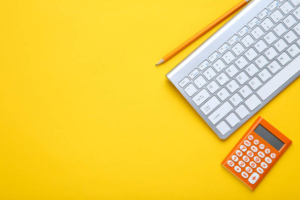 Computer keyboard with calculator and pencil on yellow backgroun - Foto, afbeelding