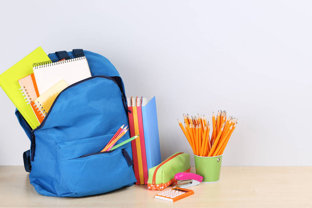 Backpack with school supplies on grey background - Foto, immagini