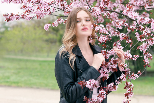 Bahar gününde çiçek açması tree yakınındaki güzel genç kadın - Fotoğraf, Görsel