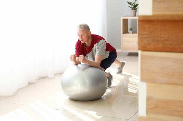 Jeune homme faisant de l'exercice avec fitball à la maison
 - Photo, image