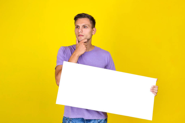 Young man with blank board on yellow background - Valokuva, kuva