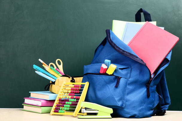 Backpack with school supplies on green background - Фото, изображение