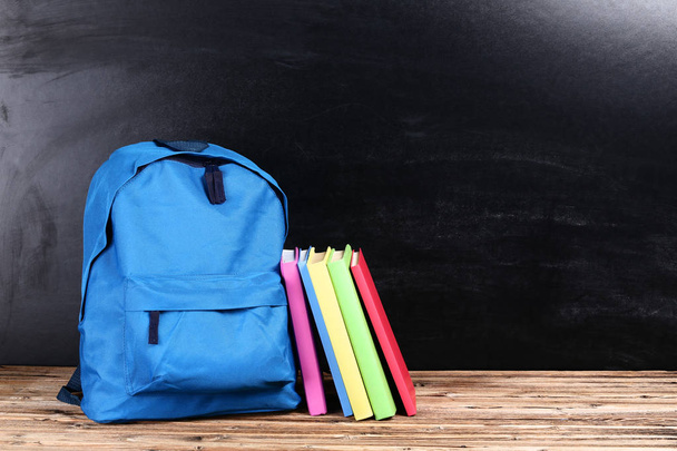 Backpack with colorful books on black background - Zdjęcie, obraz