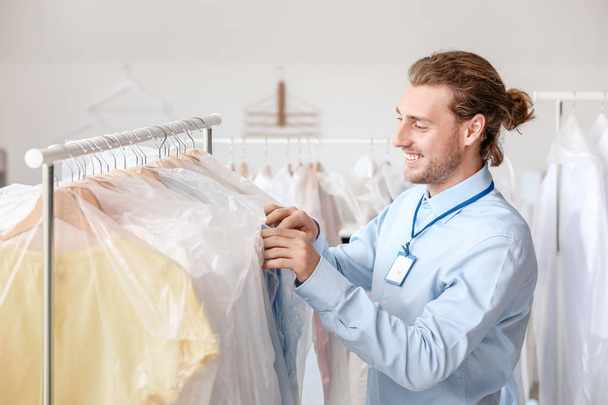 Worker of modern dry-cleaner's near rack with clothes - Fotoğraf, Görsel