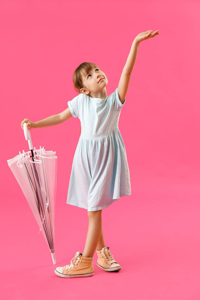 Cute little girl with umbrella on color background - Фото, изображение