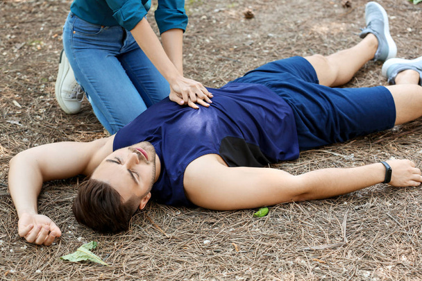 Mujer dando RCP al hombre inconsciente al aire libre
 - Foto, Imagen