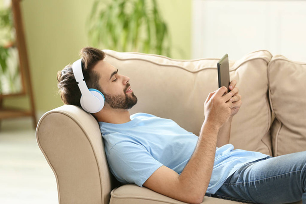 Joven escuchando audiolibro en casa
 - Foto, imagen