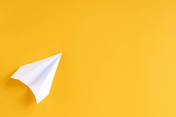 White paper plane on yellow background composition. - Foto, afbeelding