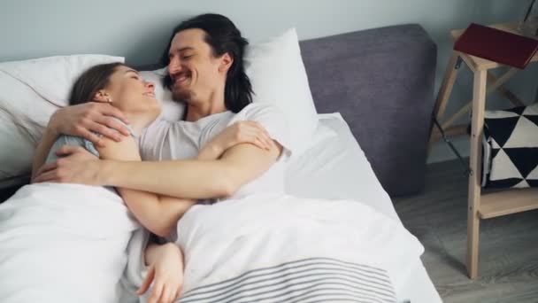 Mąż i żona w piżamie mówi przytulanie w łóżku w sypialni w domu - Materiał filmowy, wideo