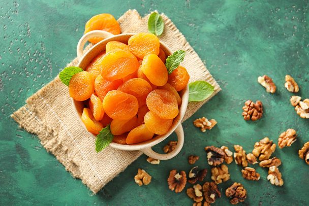 Pot with dried apricots on color background - Foto, imagen