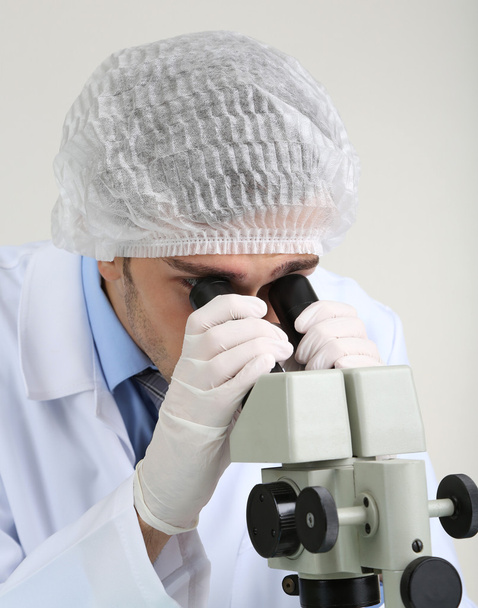 Young laboratory scientist looking at microscope in lab - Foto, imagen