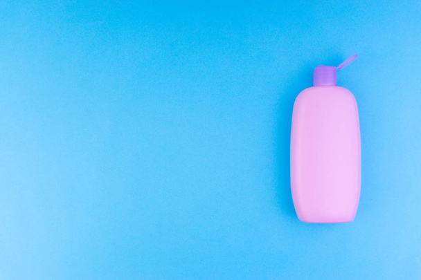 flache Komposition von Babypflegeprodukten auf blauem Hintergrund. Blick von oben auf Shampoo oder Duschgel - Foto, Bild