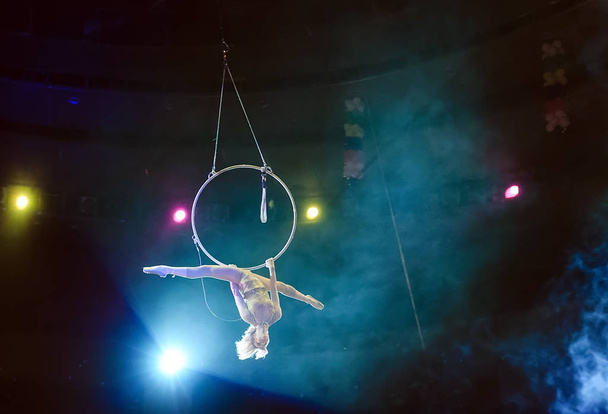 Aerial acrobat in the ring. A young girl performs the acrobatic elements in the air ring. - Fotó, kép