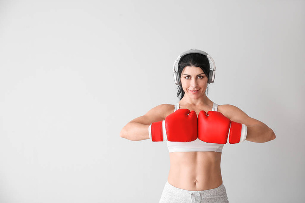 Sporty female boxer with headphones on white background - Photo, Image