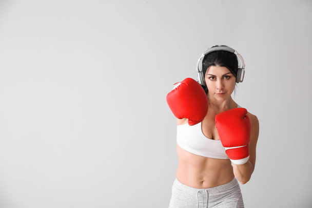 Αθλητικό θηλυκό μπόξερ με ακουστικά σε λευκό φόντο - Φωτογραφία, εικόνα