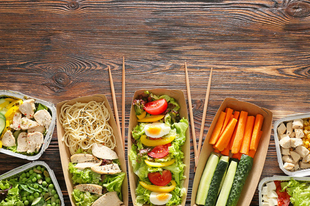 Containers with delicious food on wooden background - Foto, Imagen