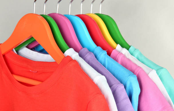 Different shirts on colorful hangers on grey background - Foto, Bild