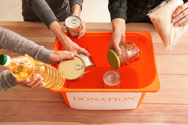 Voluntarios poniendo comida de donación en caja en la mesa
 - Foto, Imagen