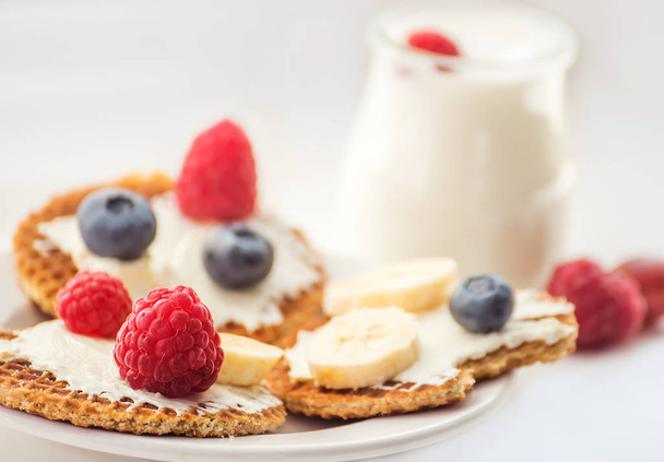 Waffles with cheese, yogurt and raspberries. A delicious wholesome breakfast on a light background. Very soft selective focus. - Фото, изображение