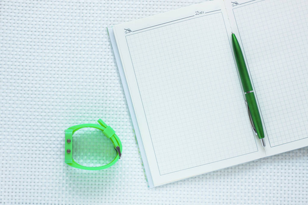 Зеленый ноутбук моды и карандаш на белом текстурированном фоне. Top view, flat lay
 - Фото, изображение