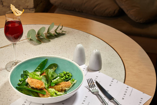 Rebanadas de pollo crujiente aderezadas en un plato azul servido en una mesa con un mantel blanco.. - Foto, imagen