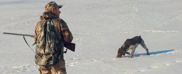 Jäger mit Gewehr und Hund auf den ersten Schnee in der Steppe, Jagd Fasan in reflektierender Weste - Foto, Bild