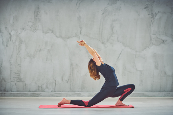 Young slim woman doing lunge on the Knee yoga posture. - Photo, image