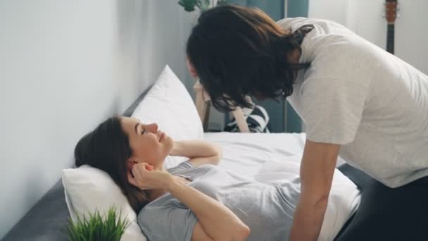 Happy young people man and woman taking pictures with modern camera in bed - Video