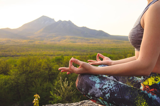 Young woman practicing yoga or pilates at sunset or sunrise in beautiful mountain location. - Photo, image